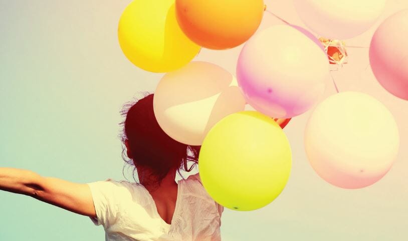 a young lady holding balloons.