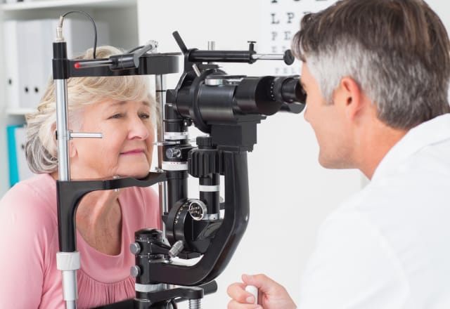 opthamologist examining patients eyes with special instrument